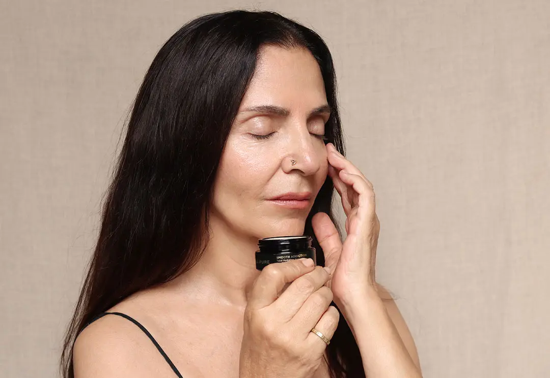 Woman applying LE PURE Smooth Addiction balm to her face – certified organic protective skincare to shield sensitive skin from pollen and environmental aggressors