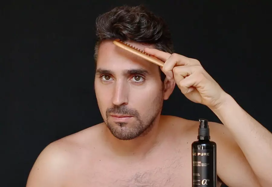 Un homme se brosse les cheveux dans le cadre d'un traitement pour renforcer les cheveux, avec une bouteille de sérum Alpha Hair de LE PURE devant lui.