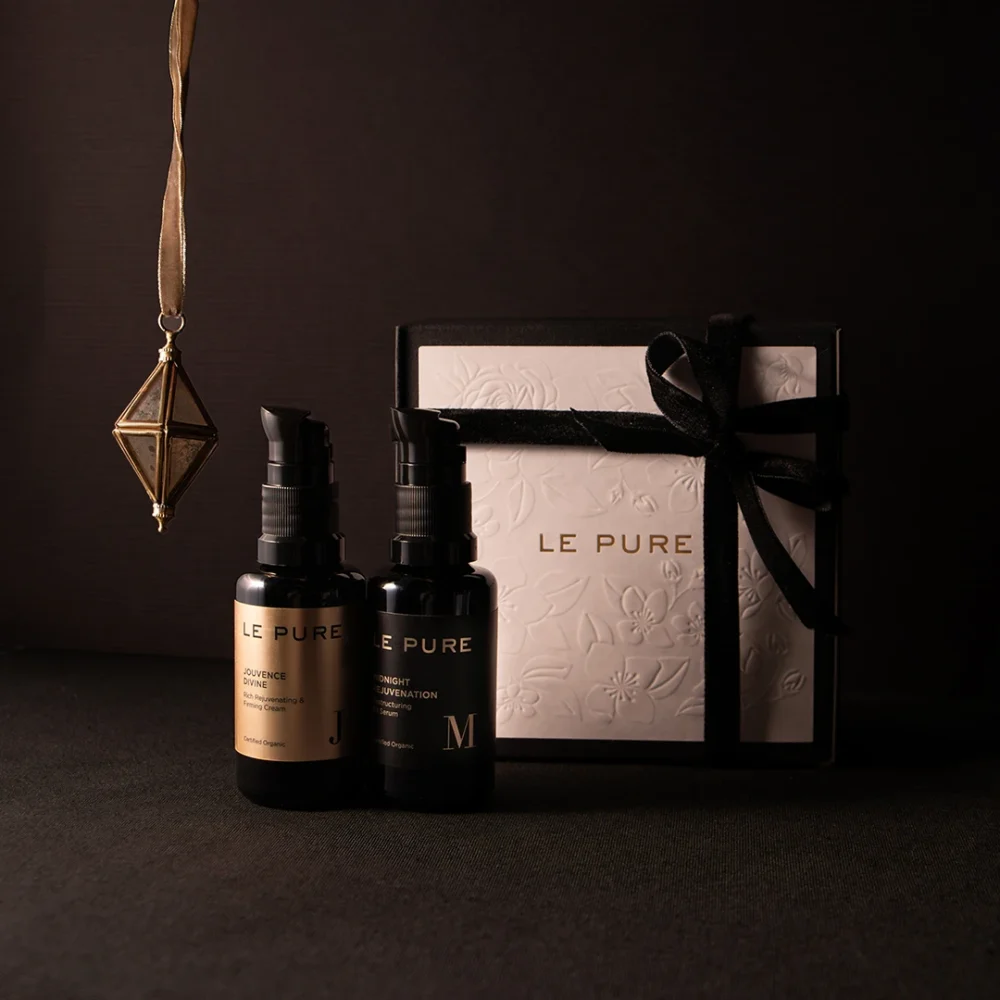 Elegant LE PURE gift set featuring two black bottles and a white box tied with a black ribbon, captured in a refined dark setting.