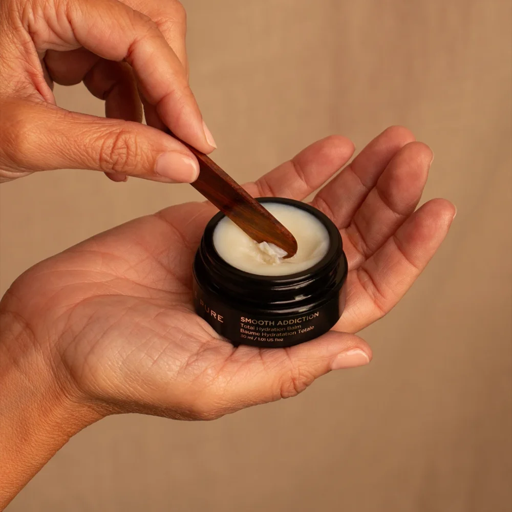 Mains appliquant le baume Smooth Addiction à l’aide d’une spatule – soin primé, idéal pour l’hiver